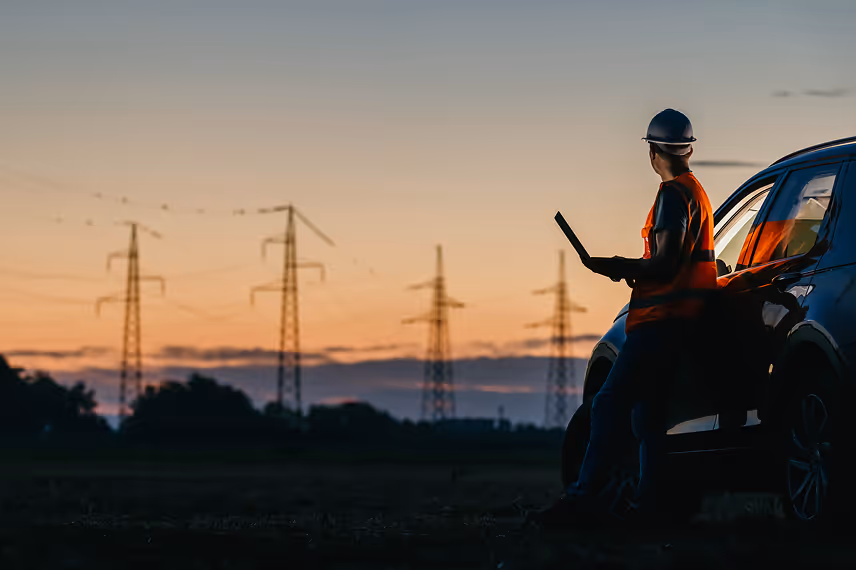 A worker wearing security gear looking at a power line